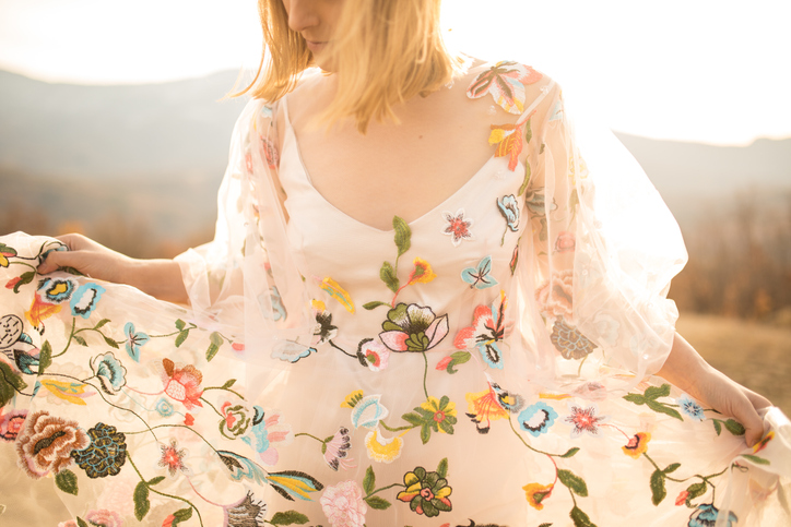 Young woman in a romantic dress enjoying in the field