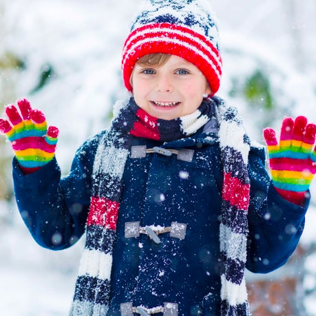 Young kind in red hat and gloves. Snowy day.