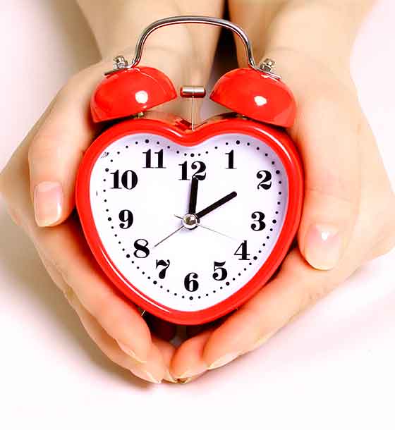 View our hours of operation. Red heart shaped clock in hand.