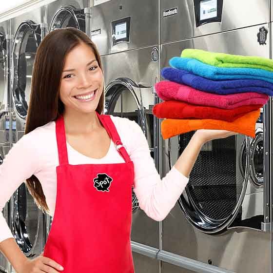 Spot laundromat attendant holding stack of fresh folded towels.