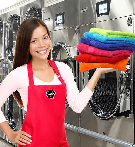 Spot laundromat attendant holding stack of fresh folded towels. 